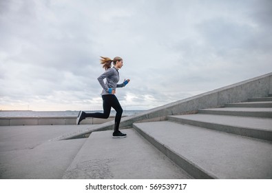 Side view shot of fitness woman running up on steps. Female runner athlete going up stairs. - Powered by Shutterstock