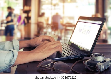 Side View Shot Of Young Business Man Hands Busy Working On His Laptop Sitting At Wooden Table In A Coffee Shop With Retro Filter Effect