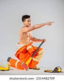 Side view shows a professional firefighter sitting and kneeling down with one hand holding an iron axe and the other hand pointing a finger.