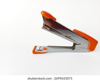 Side view of silver stapler with orange handle on white background, office stationery tool for paper binding.