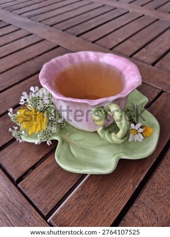 Side view of a single cone-shaped pink tea cup resembling a flower, with organic green tea and natural wildflowers.