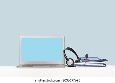 Side View Of Slim Laptop With Headphones Headset On White Desk. Mockup Screen. Distant Learning. Working From Home, Online Courses Or Support. Audio Podcast. Helpdesk Or Call Center Banner