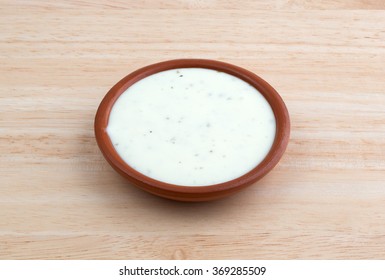 Side View Of A Small Bowl Of Ranch Dressing On A Wood Table Top Illuminated With Natural Light.