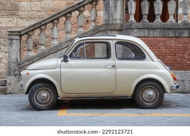 A side view of an small Italian car and an old facade in the background  