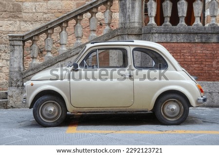 A side view of an small Italian car and an old facade in the background  