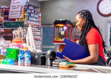 side view of a smiling African American cashier recording stocking using laptop holing clipboard - Powered by Shutterstock