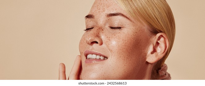 Side view of smiling blond woman with freckles touching her face. Close-up studio shot of young positive female with closed eyes against pastel background. - Powered by Shutterstock