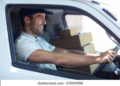 Side View Of Smiling Delivery Man Driving Van