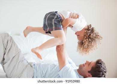 Side View Of Smiling Father Lifting His Child