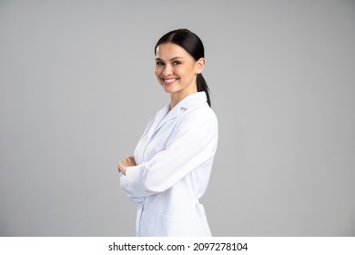 Side view of the smiling female doctor in lab coat with arms crossed looking away and posing against grey background. Medicine concept  - Shutterstock ID 2097278104
