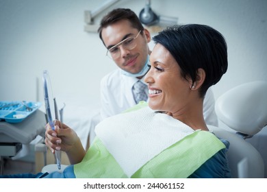 Side View Of Smiling Female Patient With Dentist In The Dentists Chair