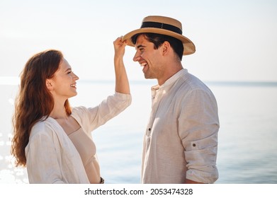 Side view smiling happy young couple two family man woman in casual clothes girlfriend put hat on boyfriend rest date at sunrise over sea sand beach ocean outdoor seaside in summer day sunset evening - Powered by Shutterstock