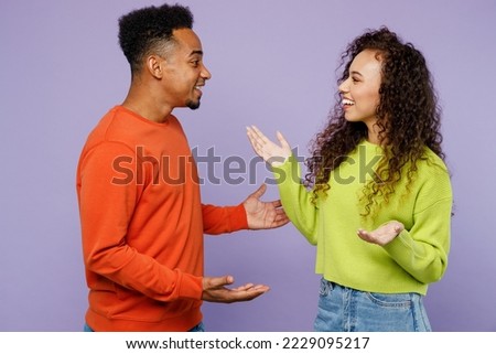 Side view smiling happy young couple two friends family man woman of African American ethnicity wear casual clothes together talk speak meet each other isolated on pastel plain light purple background