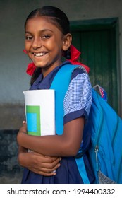 Side view Smiling Indian Rural School Girl holding notebook in school