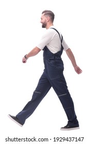 Side View. Smiling Man In Overalls Confidently Striding Forward