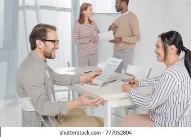 side view of smiling multiethnic middle aged people talking while working together 