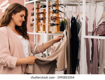 Side View Of A Smiling Plus Size Woman Shopping In A Small Clothing Store