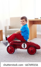 Side View Of Smiling Small Boy Sitting On Retro Red Car 