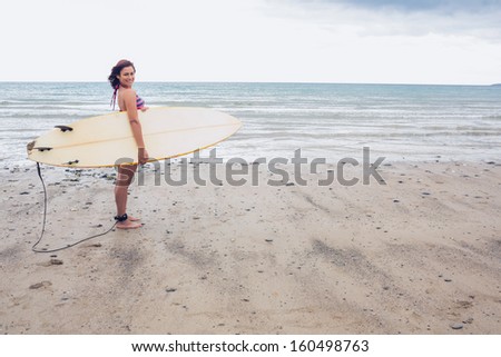 Young surfer woman with top and bikini holding surfboard