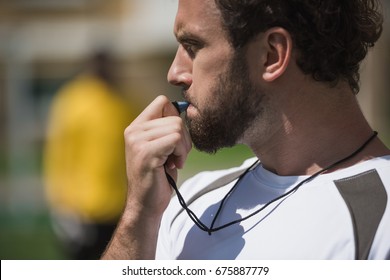 Side View Of Soccer Referee Whistling In Whistle On Soccer Pitch During Game