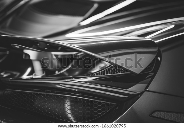 Side view of the spoiler and stop light of a sports\
car in black and white