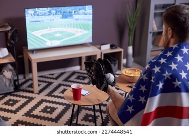 Side view of sports fan watching baseball match at home on TV and wearing USA flag, copy space - Powered by Shutterstock