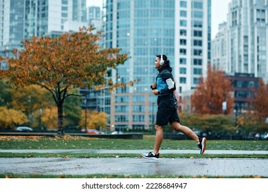 Side view of sportsman running while exercising in the park during rainy day.  - Powered by Shutterstock