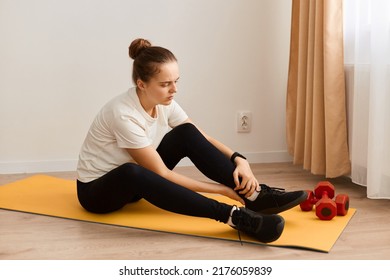 Side View Of Sporty Athletic Woman With Bun Hairstyle Wearing White T Shirt And Black Leggins Injured Her Ankle During Sporty Training, Incorrect Exercise Technique.