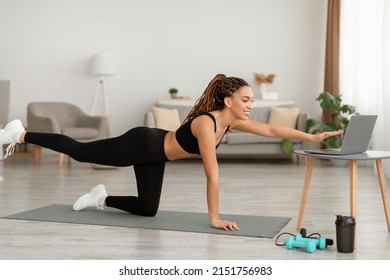 Side View Of Sporty Black Woman Doing Hip And Leg Exercise All Fours Extention Near Laptop Watching Online Workout Flexing Muscles At Home. Domestic Training Concept - Shutterstock ID 2151756983