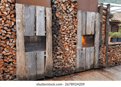Side view of stacked pile of split firewood and smokehouse