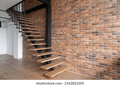 Side View Of Stairs In Cozy Loft Styled Room Interior Design. New Empty Apartment For Sale With Brick Wall. Home Environment Concept. Living Room In Industrial Style