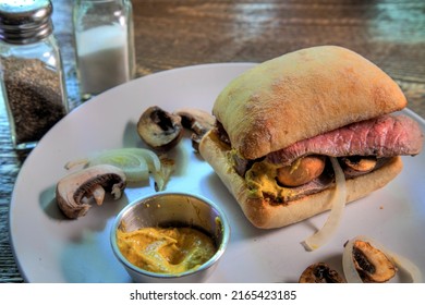 Side View Of Steak On Ciabatta Sandwich On Natural Wood Surface