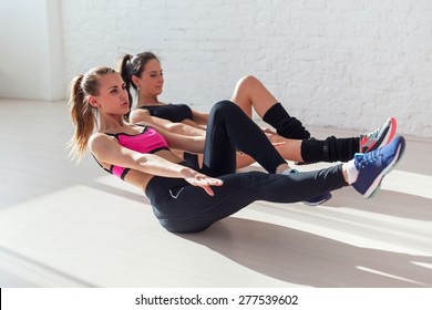 Side view of stretching at yoga class in fitness studio group of young women doing exercise abdominal crunches in the gym centre sport, training and lifestyle - Powered by Shutterstock