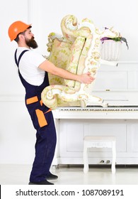 Side View Strong Bearded Guy Carrying Old Armchair In Front Of Piano. Packing The Furniture And Moving To New Place