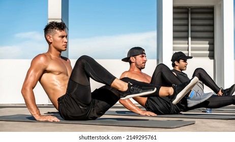 Side view of strong shirtless multiracial men doing bicycle crunches on mats during intense training outdoors in the open air rooftop - Powered by Shutterstock