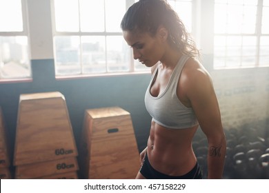 Side View Of Strong Woman Standing In The Gym. Fitness Female Taking A Break From Intense Workout.