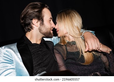 Side View Of Stylish Man Kissing Blonde Girlfriend Isolated On Black