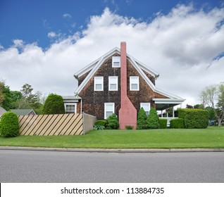 Side View Of Suburban Three Story Tall Shingle Home Brick Chimney Fence Front Yard Curb Residential Neighborhood Street