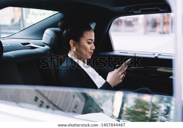 Side\
view of successful executive expert sitting on car backseat and\
reading email with info about company tutorial connected to high 4g\
internet, positive woman sending sms message via\
app