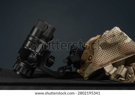 Side view of tactical night vision monocular assembly connected to shroud on multicam skull cap on dark background.