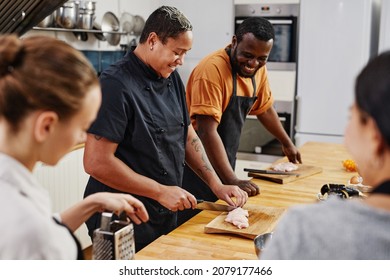 Side view at tattooed female chef cooking with diverse team in kitchen, copy space - Powered by Shutterstock