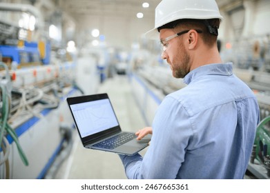 Side view of technician or engineer with headset and laptop standing in industrial factory. - Powered by Shutterstock