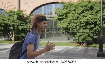 Side view of teenage boy with back pack running to school being late. Teen student hurry to class outside college building