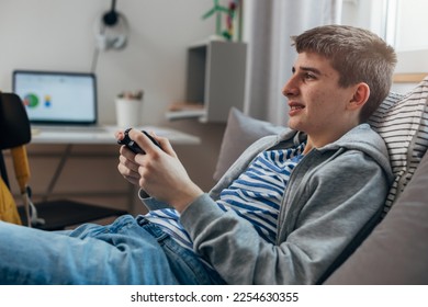 Side view of a teenage boy playing video games - Shutterstock ID 2254630355