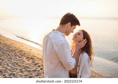 Side view tender young couple two friend family man woman in white clothes boyfriend hug girlfriend hold face going to kiss at sunrise over sea beach ocean outdoor seaside in summer day sunset evening