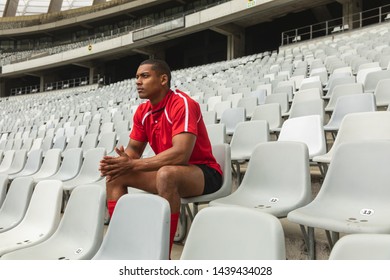 Side view of thoughtful African American male rugby player sitting alone in stadium - Powered by Shutterstock