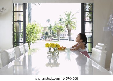 Side View Of Thoughtful Girl Sitting At Dining Table