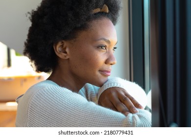 Side View Of Thoughtful Young African American Afro Woman Looking Through Window At Home. Unaltered, Lifestyle And Simple Living Concept.