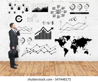 Side view of thoughtful young businessman in white brick room with wooden floor and digital charts on wall. Business concept - Powered by Shutterstock - Get 15% off with code: PIKWIZARD15