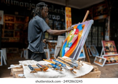 Side view three quarter length photo of a collection of brushes while african american artist painting with acrylic paint in studio - Powered by Shutterstock